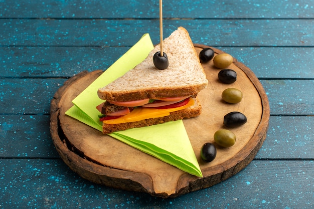 Vooraanzicht smakelijke sandwich met kaas ham binnen met olijven op blauw houten bureau