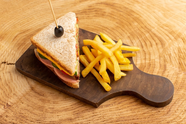 Vooraanzicht smakelijke sandwich met olijven ham tomaten groenten op houten met frietjes