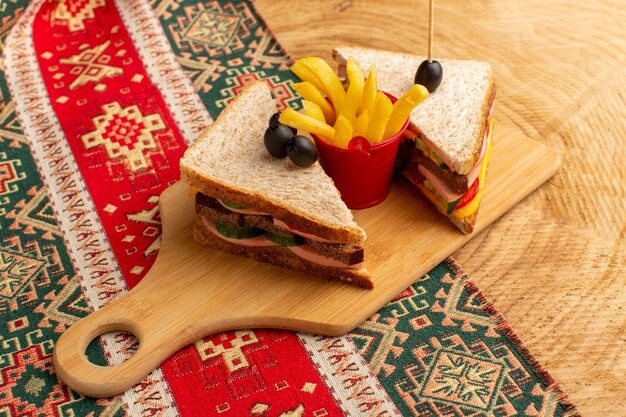 Vooraanzicht smakelijke sandwiches met olijfham-tomaten samen met frietjes op woode