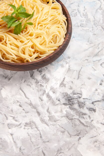 Vooraanzicht smakelijke spaghetti met groen blad op witte tafel maaltijd deeg pasta