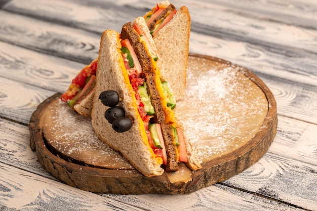 Gratis foto vooraanzicht smakelijke toastsandwiches met kaasham binnen op hout