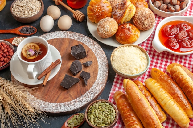 Vooraanzicht smakelijke zoete gebakjes met geleithee en broodjes op donkere muur