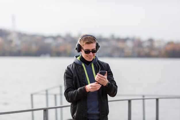 Vooraanzicht smiley blonde man buiten muziek luisteren