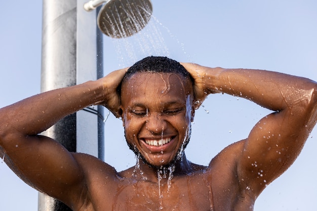 Gratis foto vooraanzicht smiley man die buiten een douche neemt