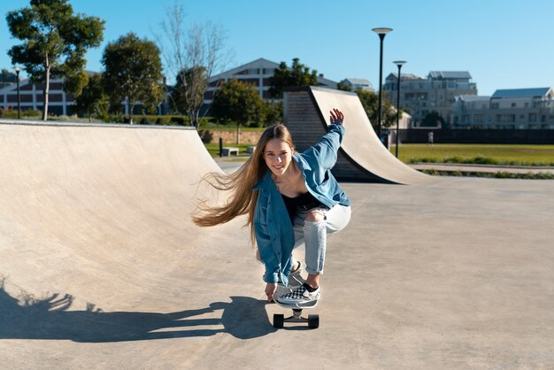 Vooraanzicht smiley meisje op skateboard buitenshuis