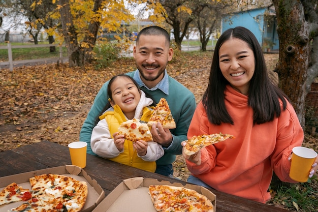 Gratis foto vooraanzicht smileyfamilie met heerlijke pizza