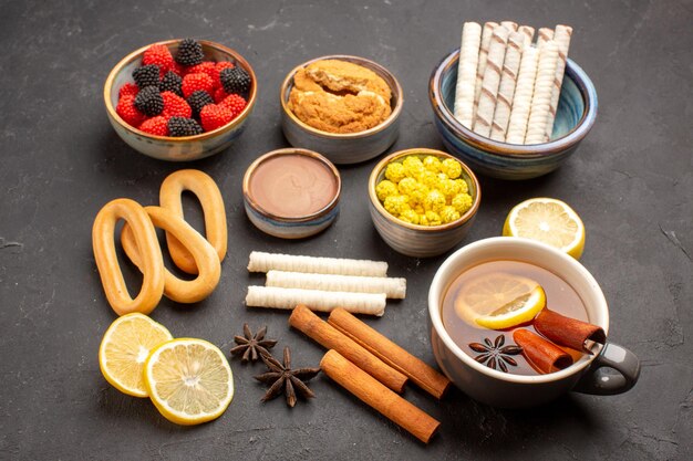 Vooraanzicht suikersnoepjes met kopje thee en koekjes op donkere achtergrond zoete snoep koekjes biscuit thee