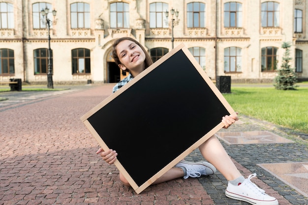 Gratis foto vooraanzicht tienermeisje bedrijf schoolbord