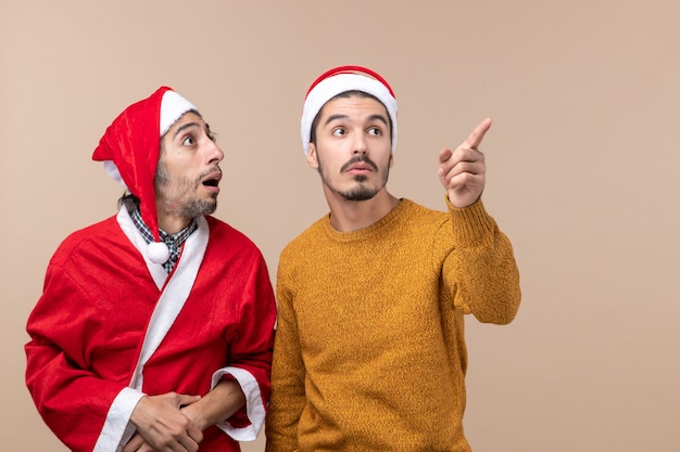 Vooraanzicht twee jonge mannen die allebei ergens op beige geïsoleerde achtergrond bekijken