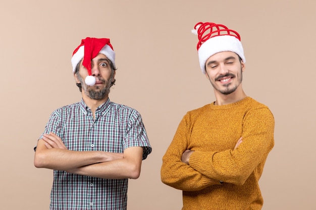 Vooraanzicht twee jonge mannen die handen op beige geïsoleerde achtergrond kruisen