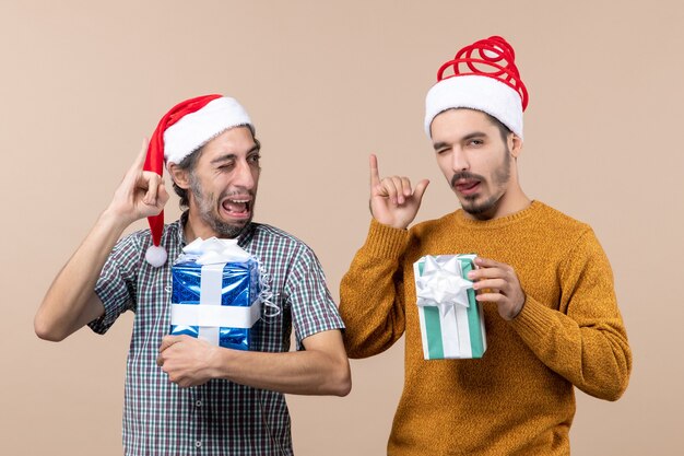 Vooraanzicht twee jongens die me een telefoongebaar maken en kerstcadeautjes vasthouden