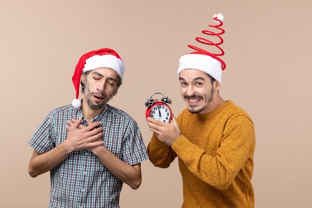 Vooraanzicht twee mannen één die zijn handen op zijn borst legt en de andere met een wekker op geïsoleerde achtergrond