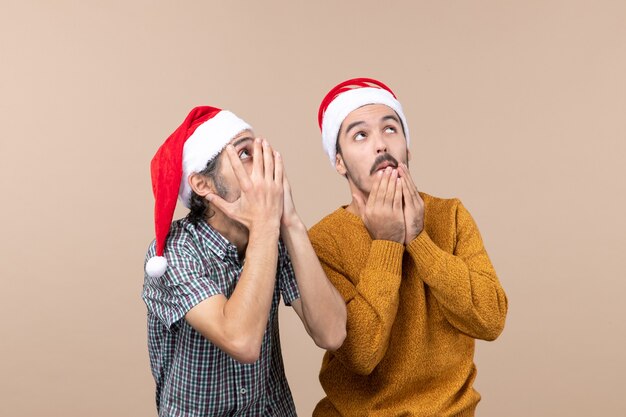 Vooraanzicht twee verbaasde mannen met santahoeden die iets met grote belangstelling op geïsoleerde achtergrond bekijken