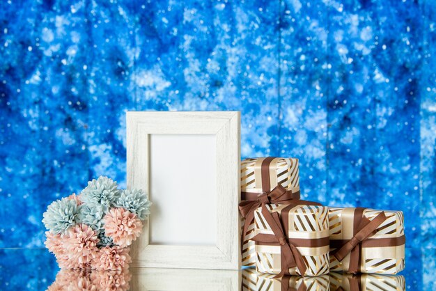 Vooraanzicht Valentijnsdag geschenken bloemen wit fotolijstje weerspiegeld op spiegel op blauwe aquarel achtergrond kopie ruimte