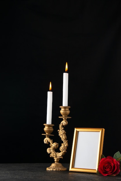 Vooraanzicht van brandende kaarsen met omlijsting als geheugen op donkere ondergrond