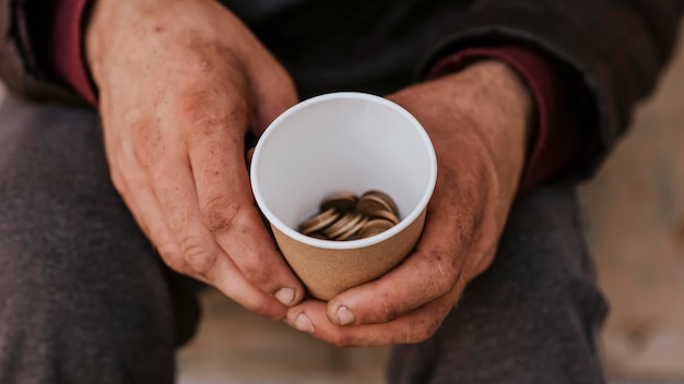 Vooraanzicht van dakloze man met beker met munten