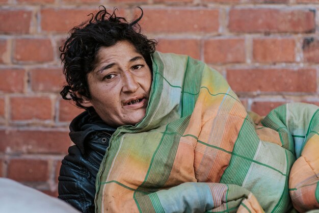 Vooraanzicht van dakloze vrouw onder deken buiten