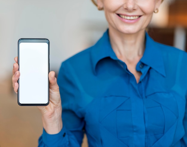 Vooraanzicht van de holdingssmartphone van de smiley oudere bedrijfsvrouw