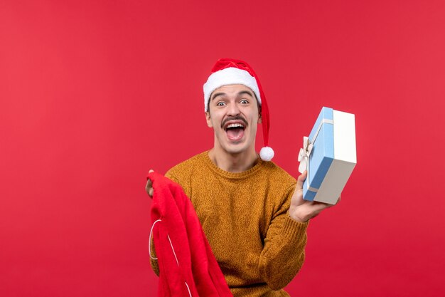 Vooraanzicht van de jonge man die geschenken uit de zak op de rode muur haalt