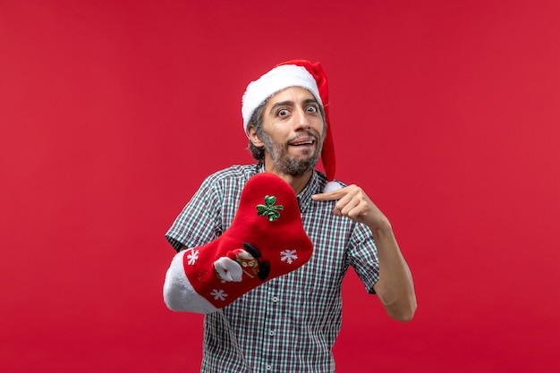 Vooraanzicht van de jonge man met Kerstmissok op rode muur