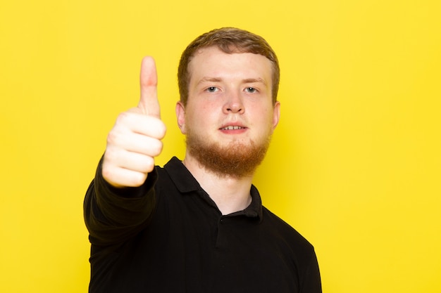 Gratis foto vooraanzicht van de jonge mens in het zwarte overhemd stellen die als teken tonen