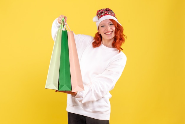 Vooraanzicht van de jonge pakketten van de vrouwenholding van winkelen op gele muur