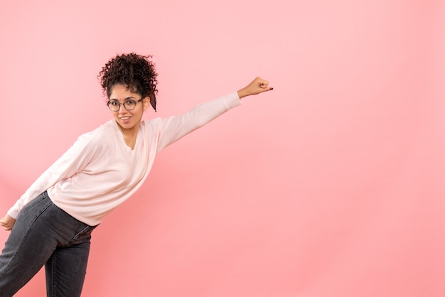 Gratis foto vooraanzicht van de jonge vrouw in superman stelt op roze muur