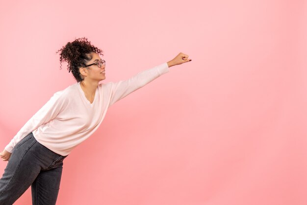 Gratis foto vooraanzicht van de jonge vrouw in superman stelt op roze muur