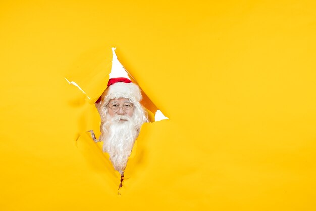 Vooraanzicht van de kerstman die door gescheurde gele muur kijkt