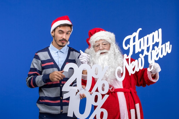 Vooraanzicht van de kerstman met een jonge man met Happy New Year en cijfers op de blauwe muur