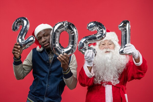 Vooraanzicht van de kerstman met jonge man met schrijven op rode muur