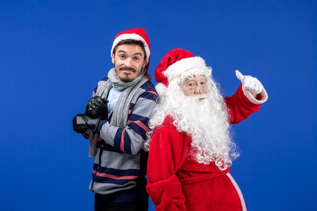 Vooraanzicht van de kerstman met jonge man op de blauwe muur