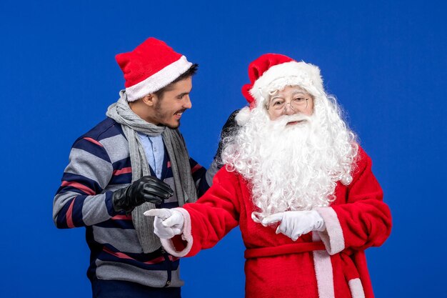 Vooraanzicht van de kerstman met jonge man op de blauwe muur