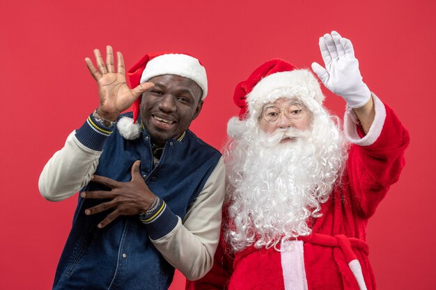 Vooraanzicht van de kerstman met jonge man op de rode muur