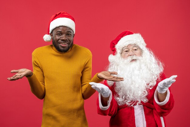 Vooraanzicht van de kerstman met jonge man op de rode muur