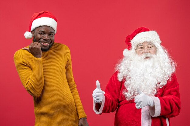 Vooraanzicht van de kerstman met jonge man op de rode muur