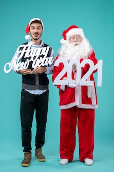 Vooraanzicht van de kerstman met man met gelukkig nieuwjaar en 2021-planken op blauwe muur