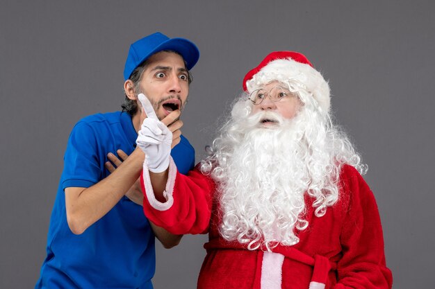 Vooraanzicht van de kerstman met mannelijke koerier op de grijze muur