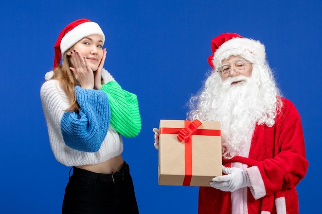 Vooraanzicht van de kerstman samen met een jonge vrouw die aanwezig is op de blauwe muur