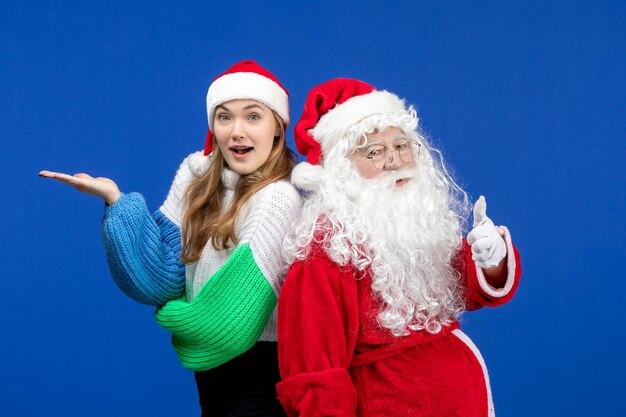 Vooraanzicht van de kerstman samen met een jonge vrouw die gewoon op de blauwe muur staat