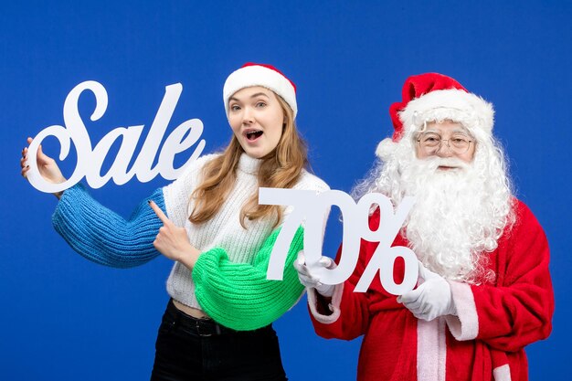 Vooraanzicht van de kerstman samen met vrouw met verkoopgeschriften op blauwe muur