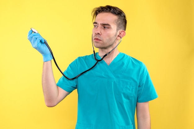 Vooraanzicht van de mannelijke stethoscoop van de artsenholding op gele muur
