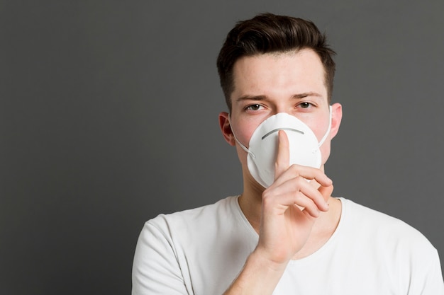 Vooraanzicht van de mens die medisch masker draagt en het stille teken maakt