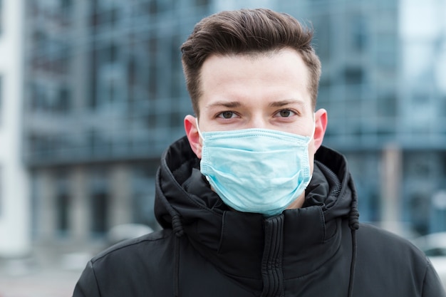 Vooraanzicht van de mens die medisch masker in de stad draagt