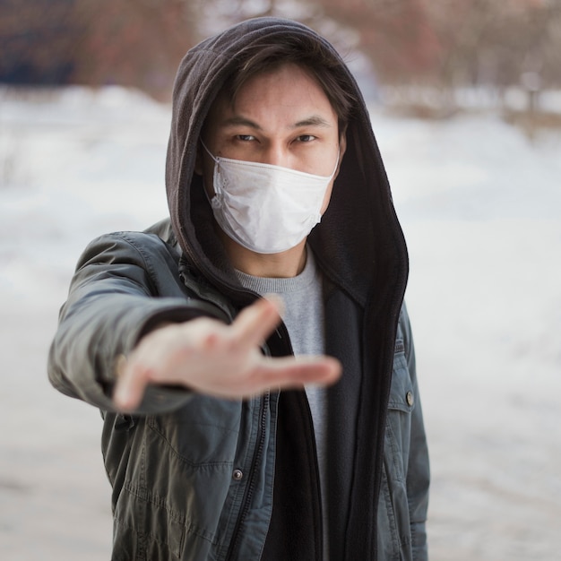 Vooraanzicht van de mens die naar iemand reikt terwijl het dragen van een medisch masker