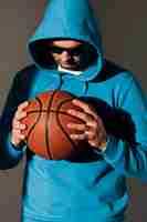 Gratis foto vooraanzicht van de mens in hoodie en zonnebril die basketbal houden