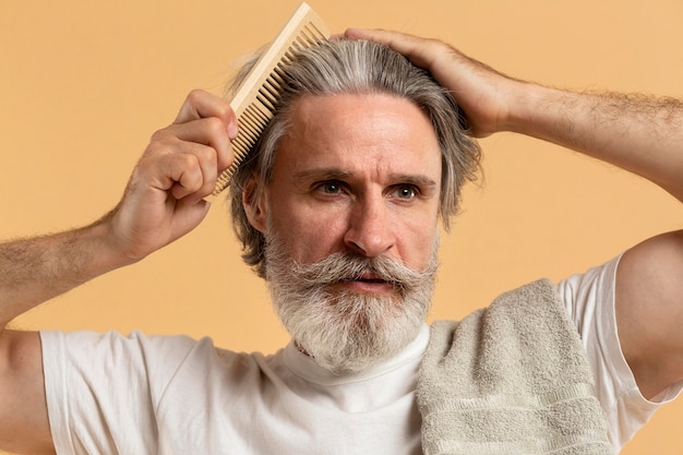 Vooraanzicht van de oudere man met baard die zijn haar kamt