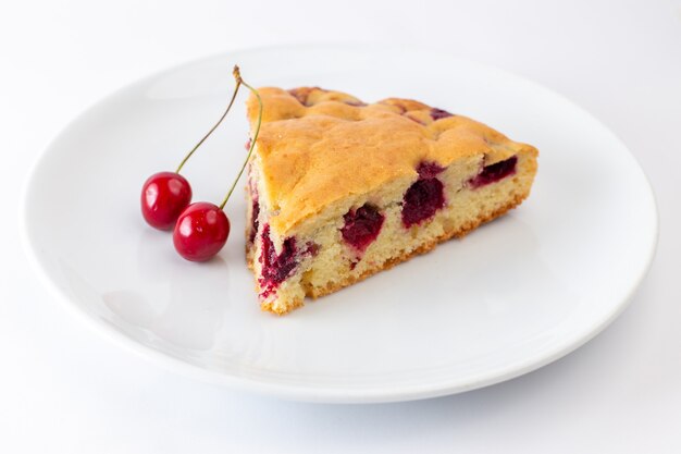 Vooraanzicht van de plak van de kersencake binnen witte plaat op de witte oppervlakte