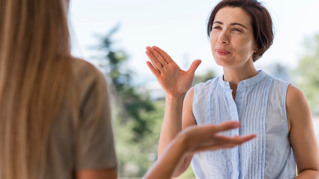 Gratis foto vooraanzicht van de vrouw die via gebarentaal communiceert terwijl ze buiten is