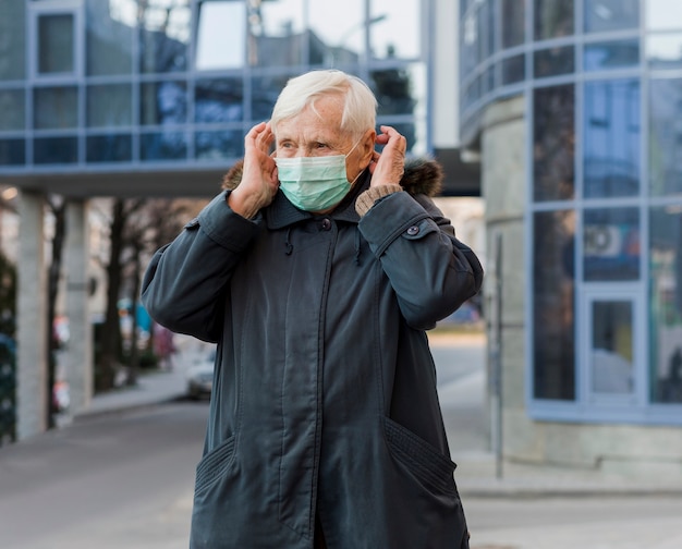 Gratis foto vooraanzicht van de vrouw met medische masker in de stad